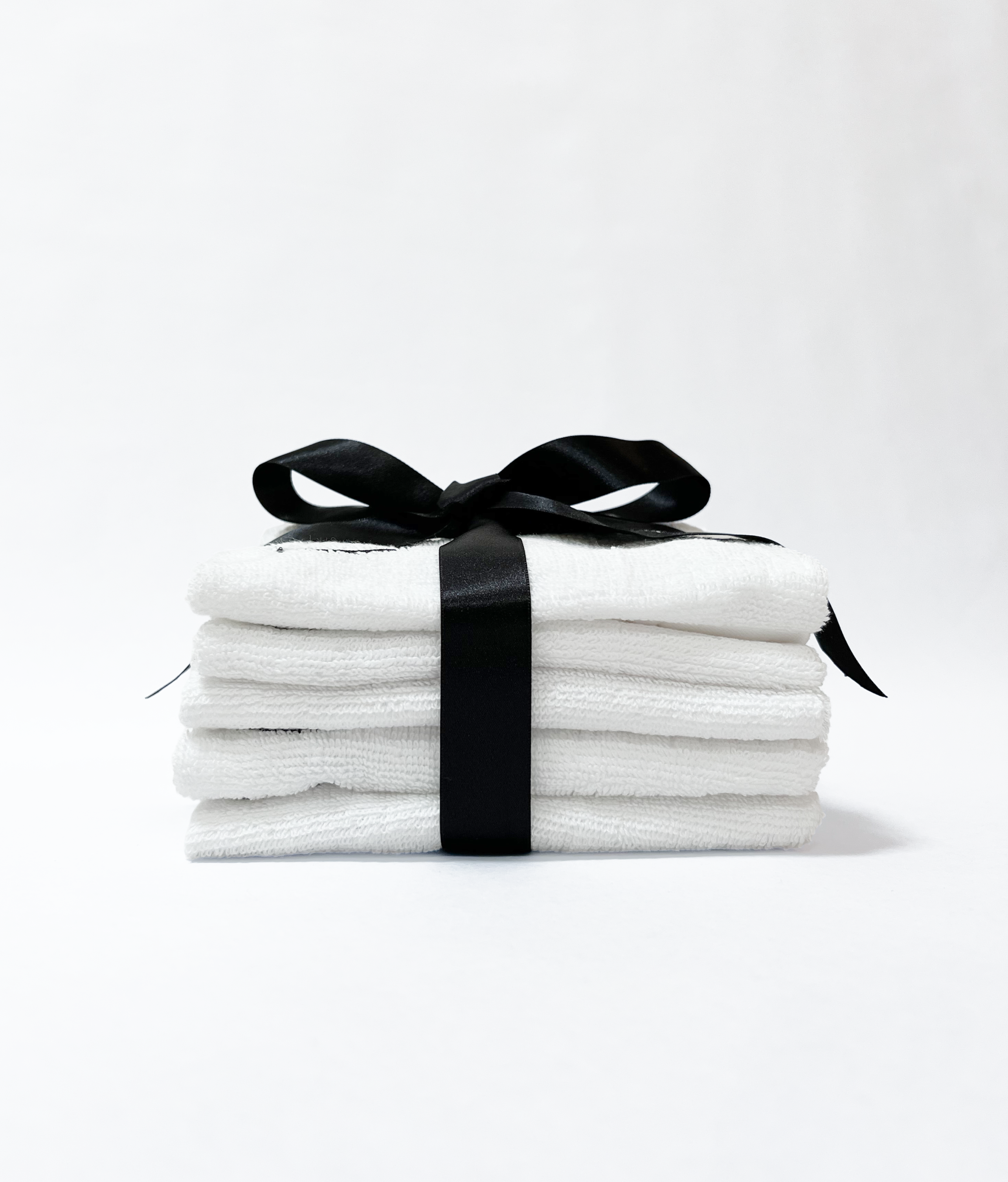 Stack of white Bumlicious BUM RAGS set embroidered with a peach logo and tied with a black satin ribbon, displayed on a clean white background.