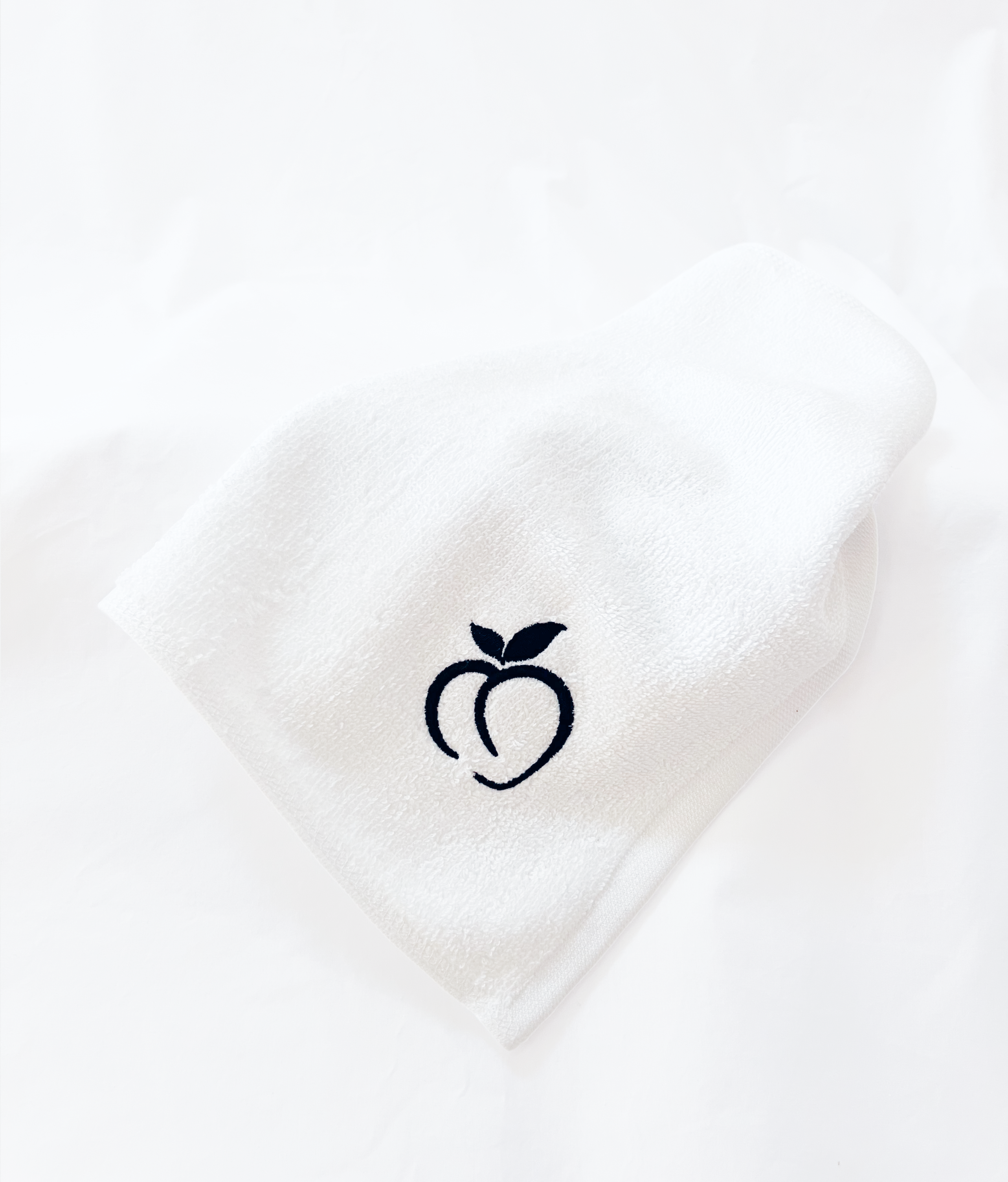 White BUM RAG with embroidered Bumlicious black peach on a white background.