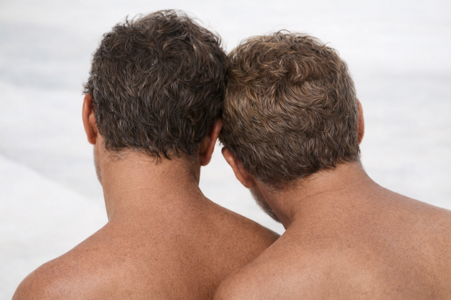 Two men with their heads close together on a plain background