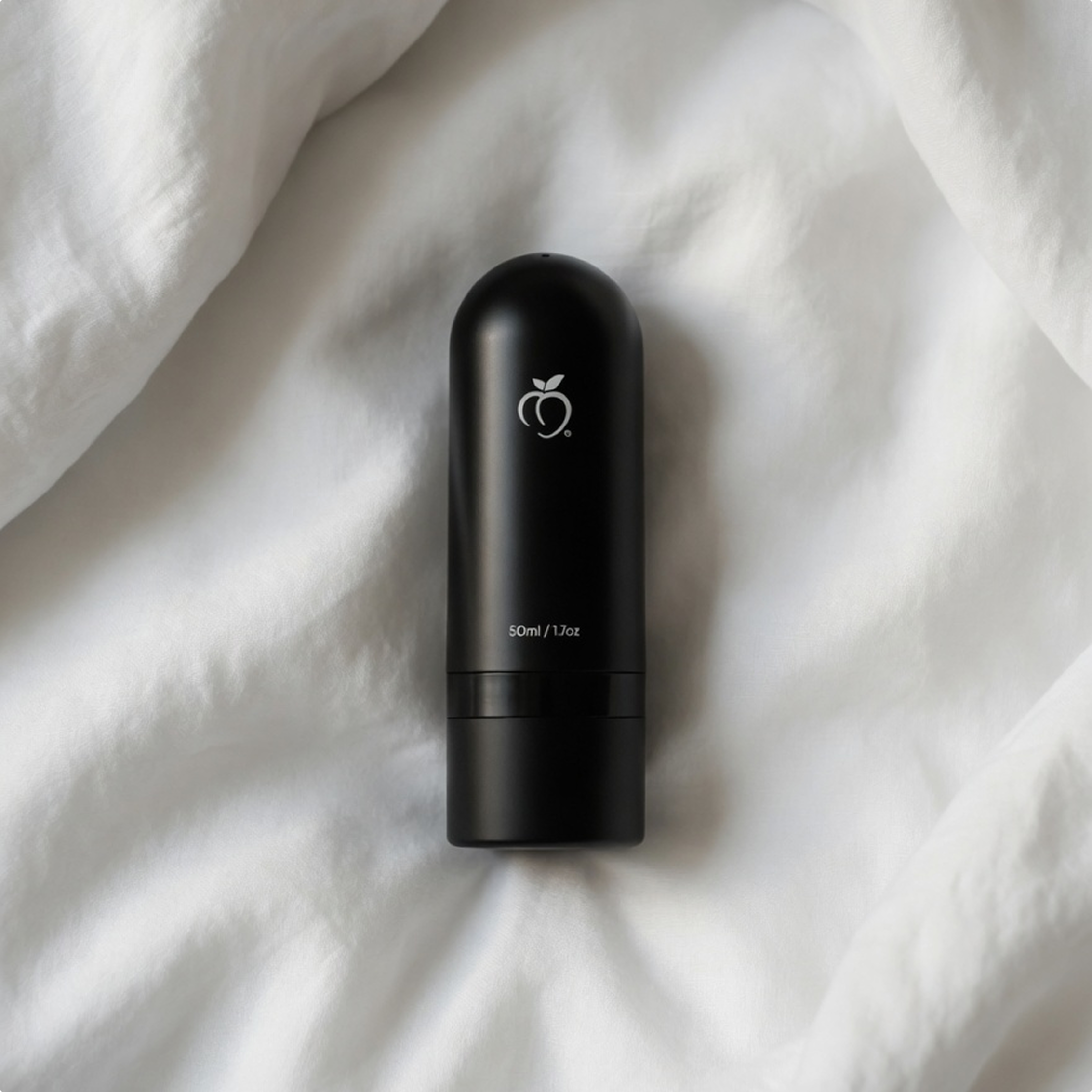 black minimalistic BUM OIL bottle on white bed sheets in sunlight