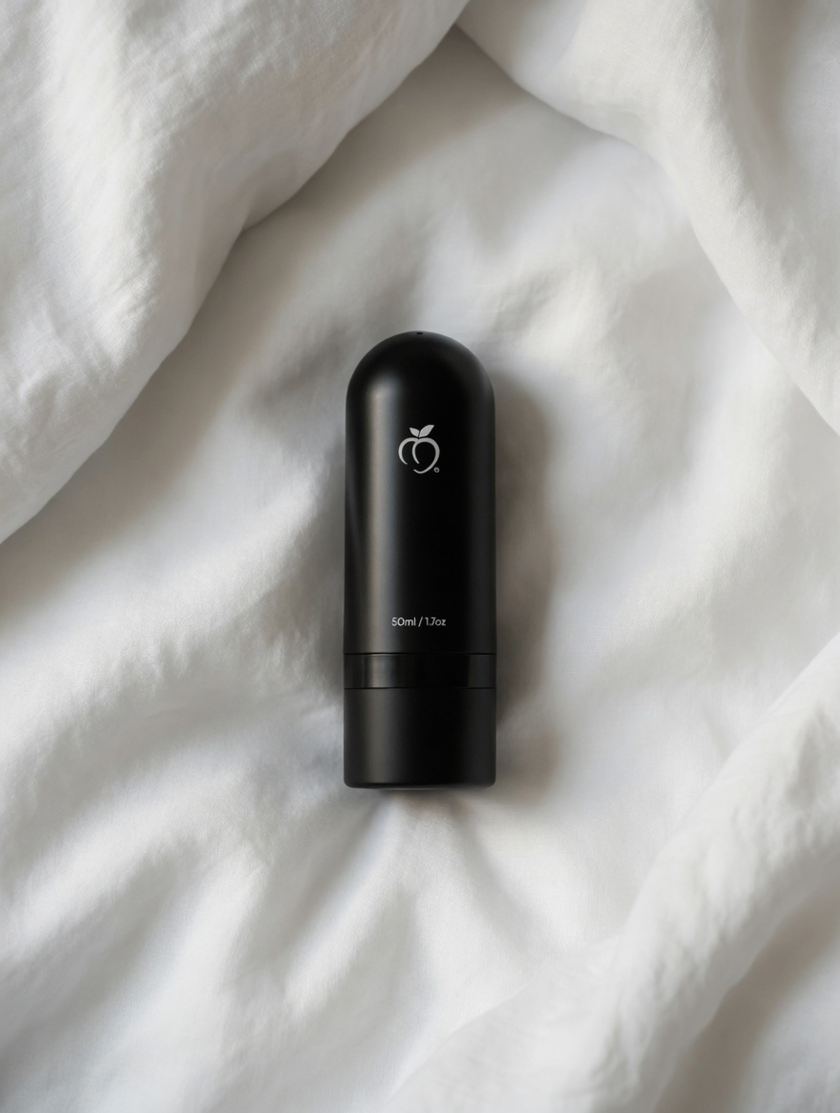 black, minimalistic BUM OIL bottle lying on white bedsheets in daylight 